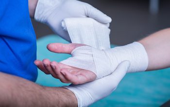 Close-up of male doctor bandaging a hand